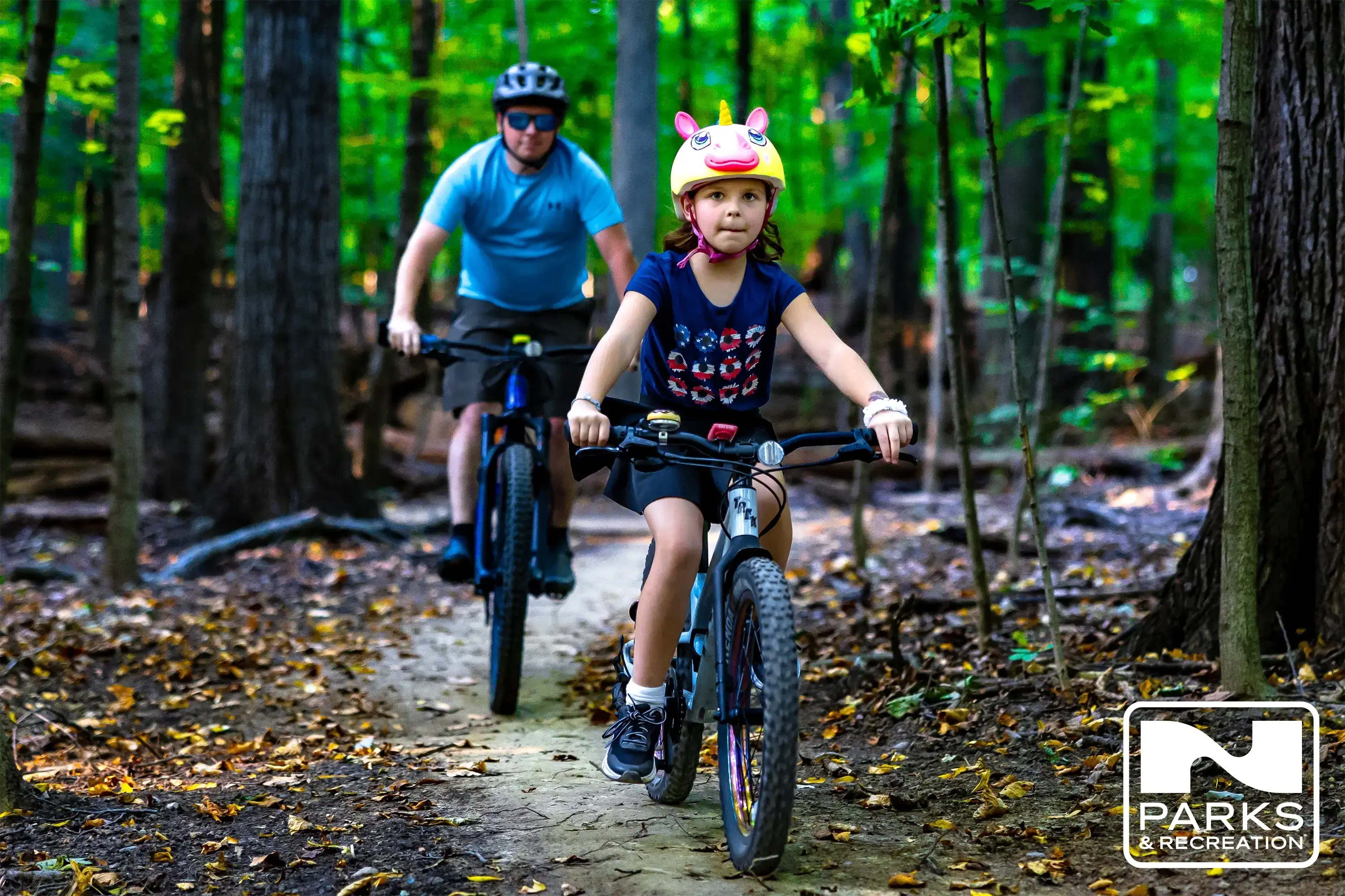 A father and daughter riding a trail on bikes