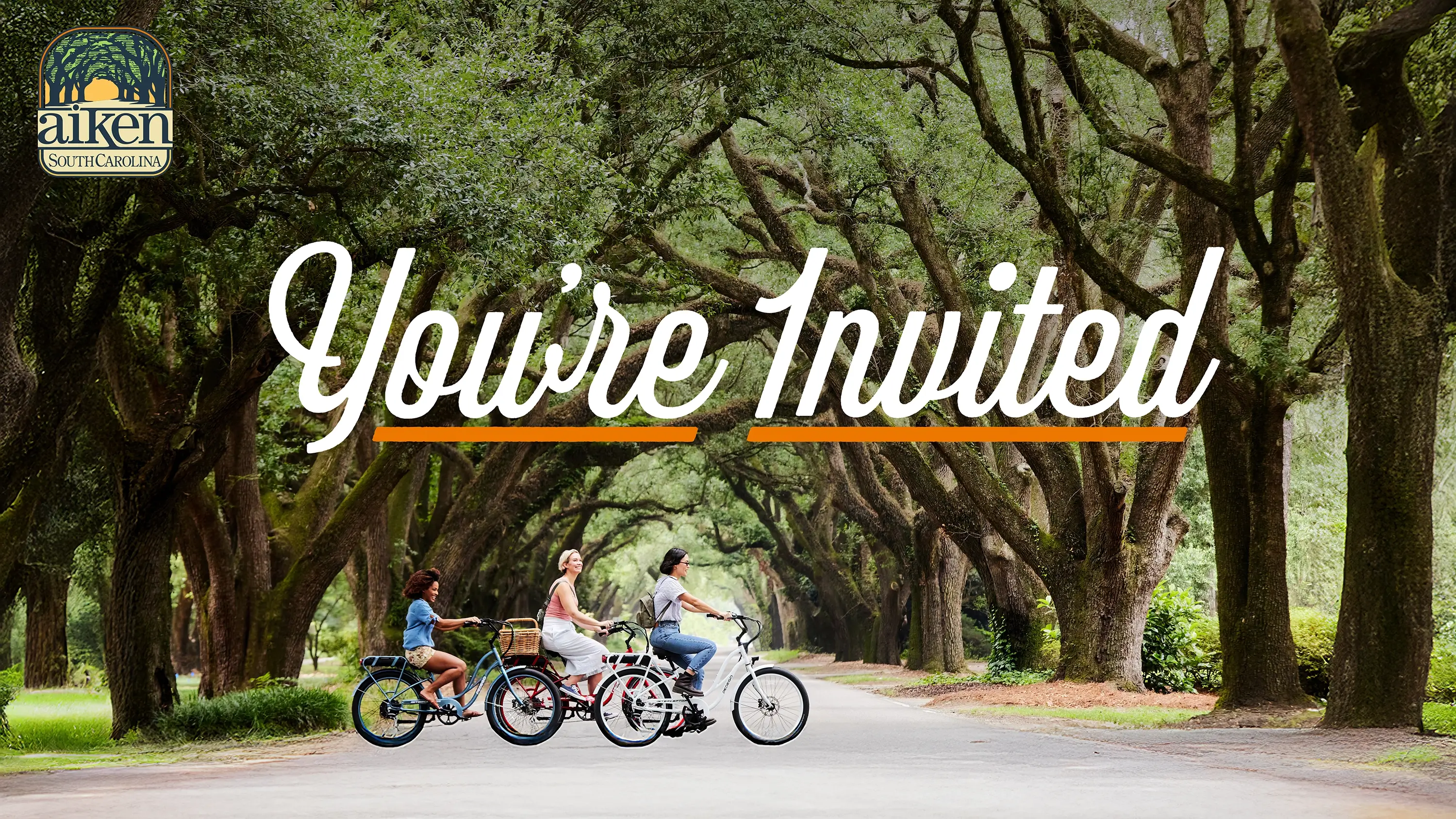 Girls biking on the street with the overlaid text "You're Invited"
