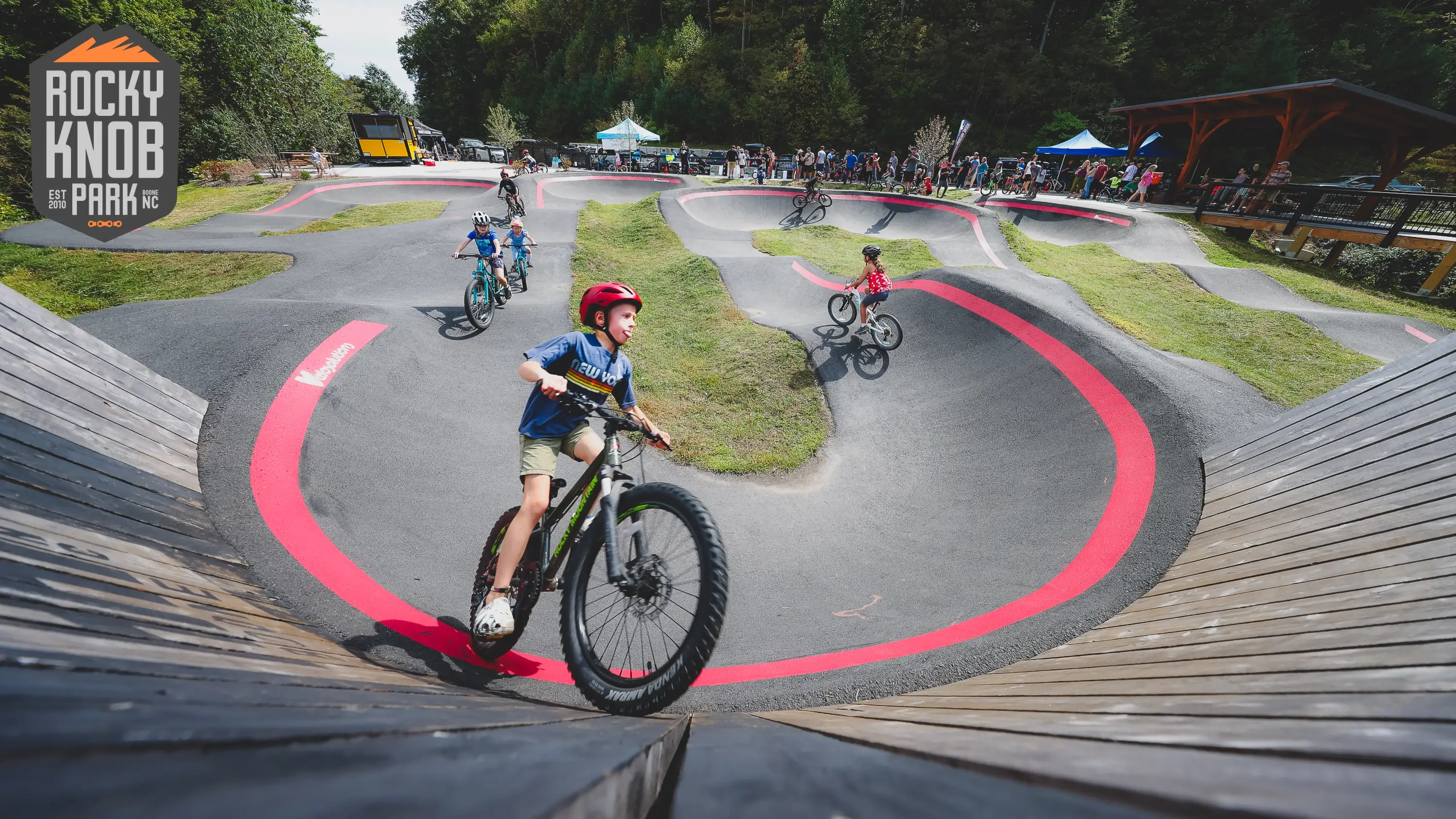 Kids riding a pump track at a ribbon cutting