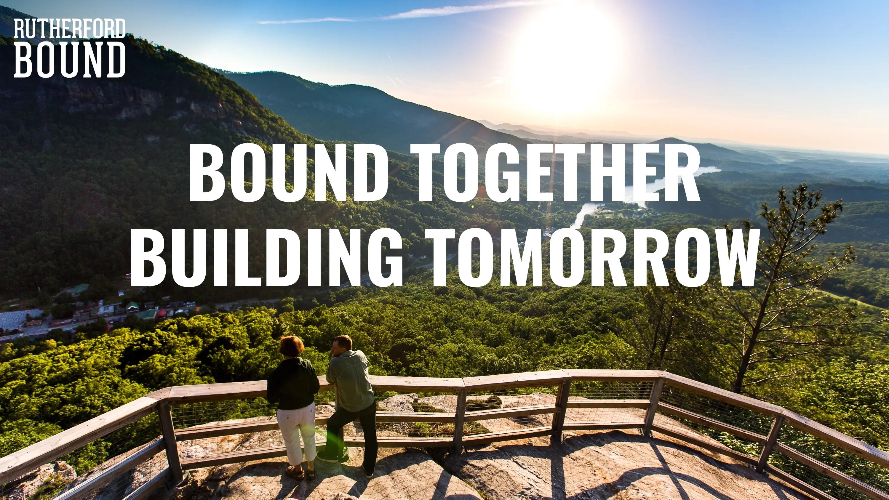 Two people standing on an overlook with the overlaid text "Bound Together Building Tomorrow"