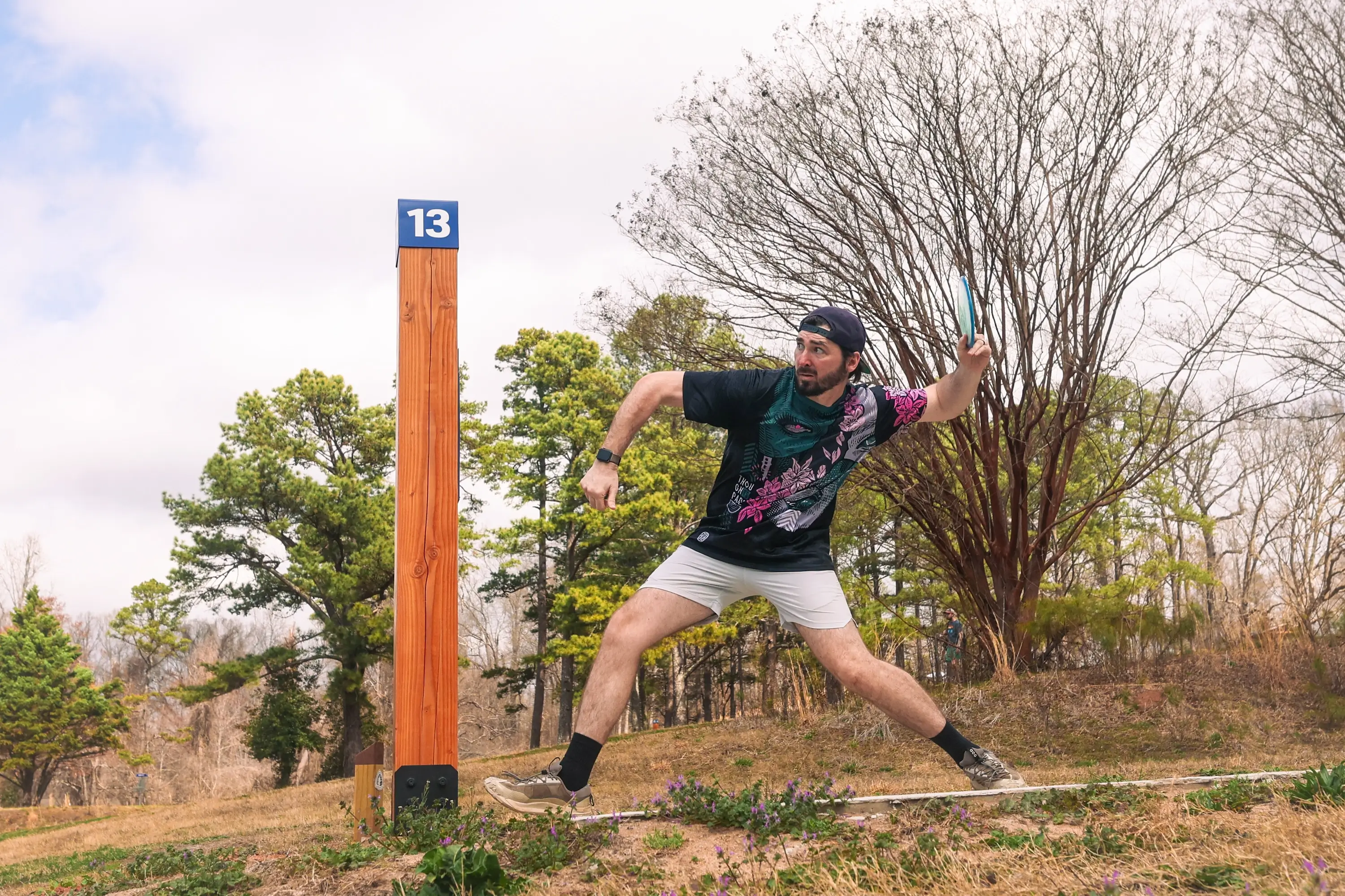 A man standing by the sign post 13 about to throw a disc