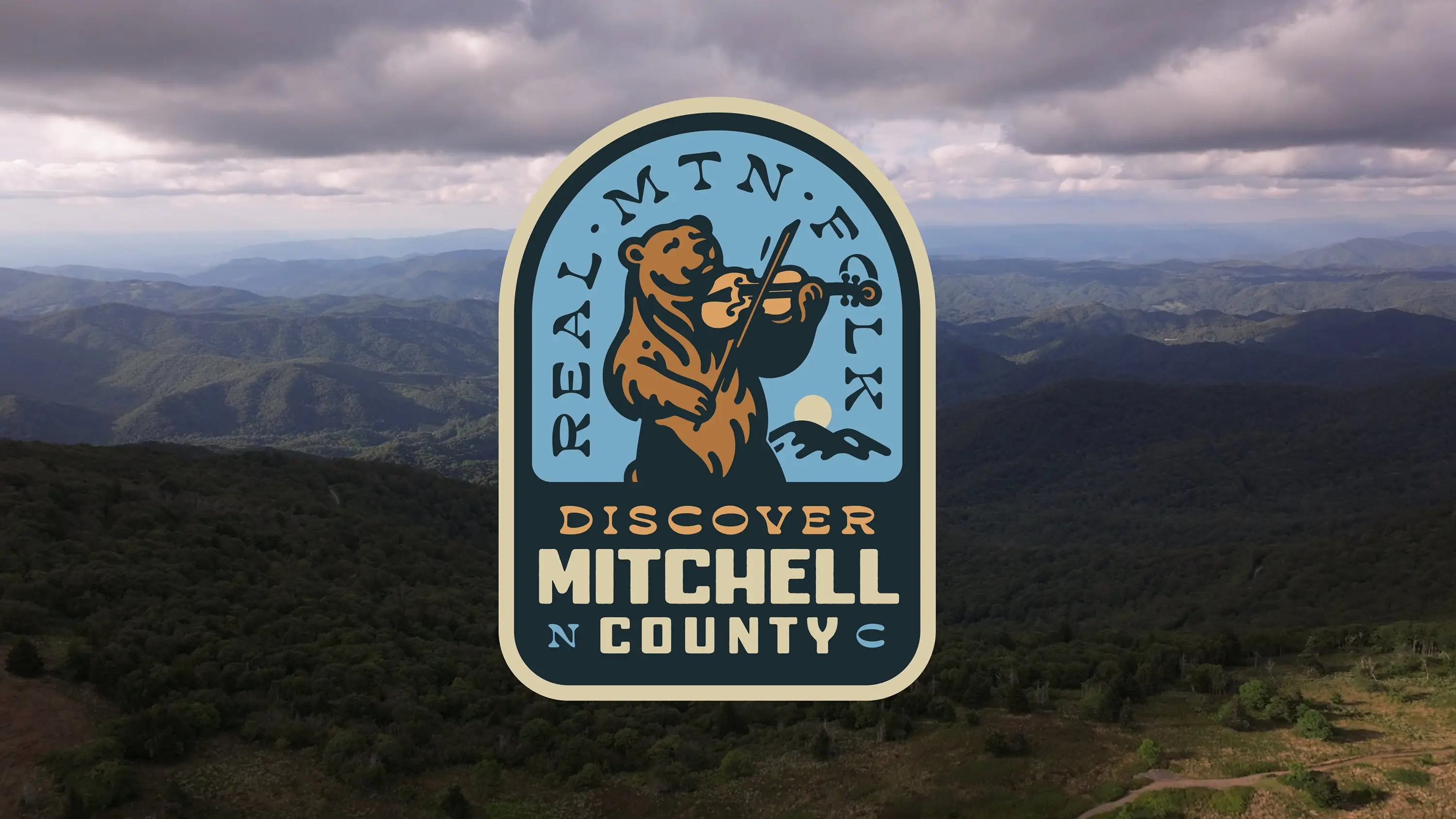 A landscape view of the foothills of the blue ridge with the overlaid Mitchell County badge mark