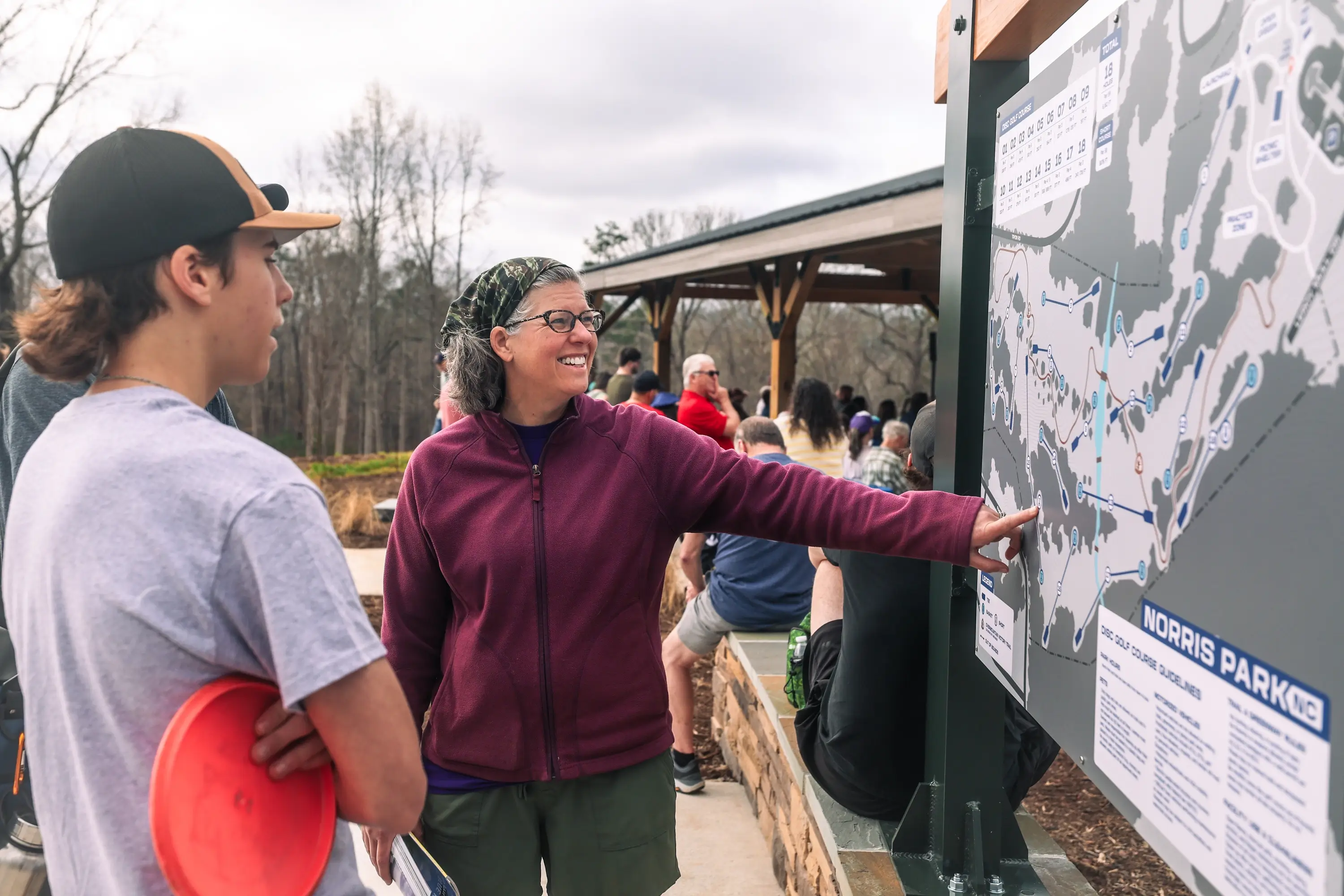 A woman by a directional map, pointing