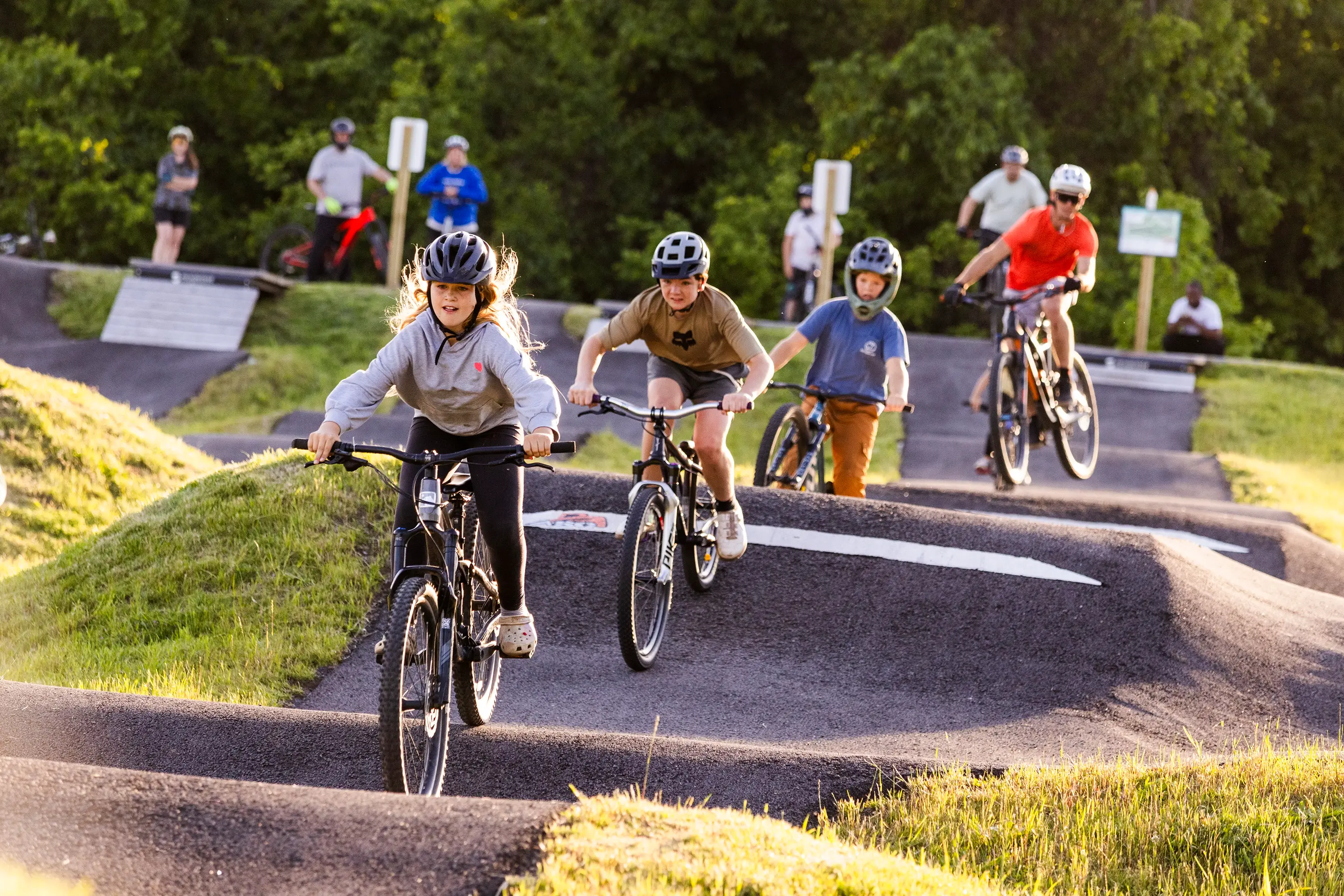 A line of people on bikes on a pump track