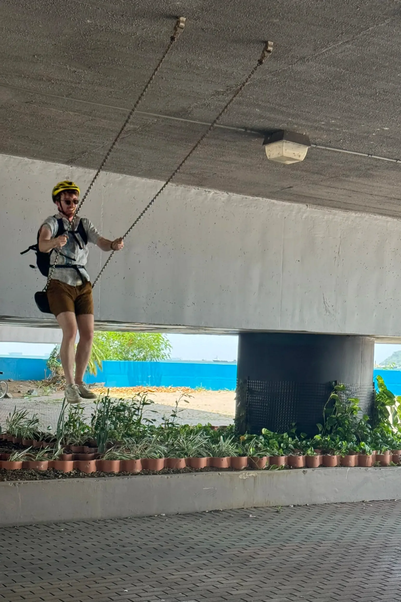 A man on a swing attached to the bottom of a bridge