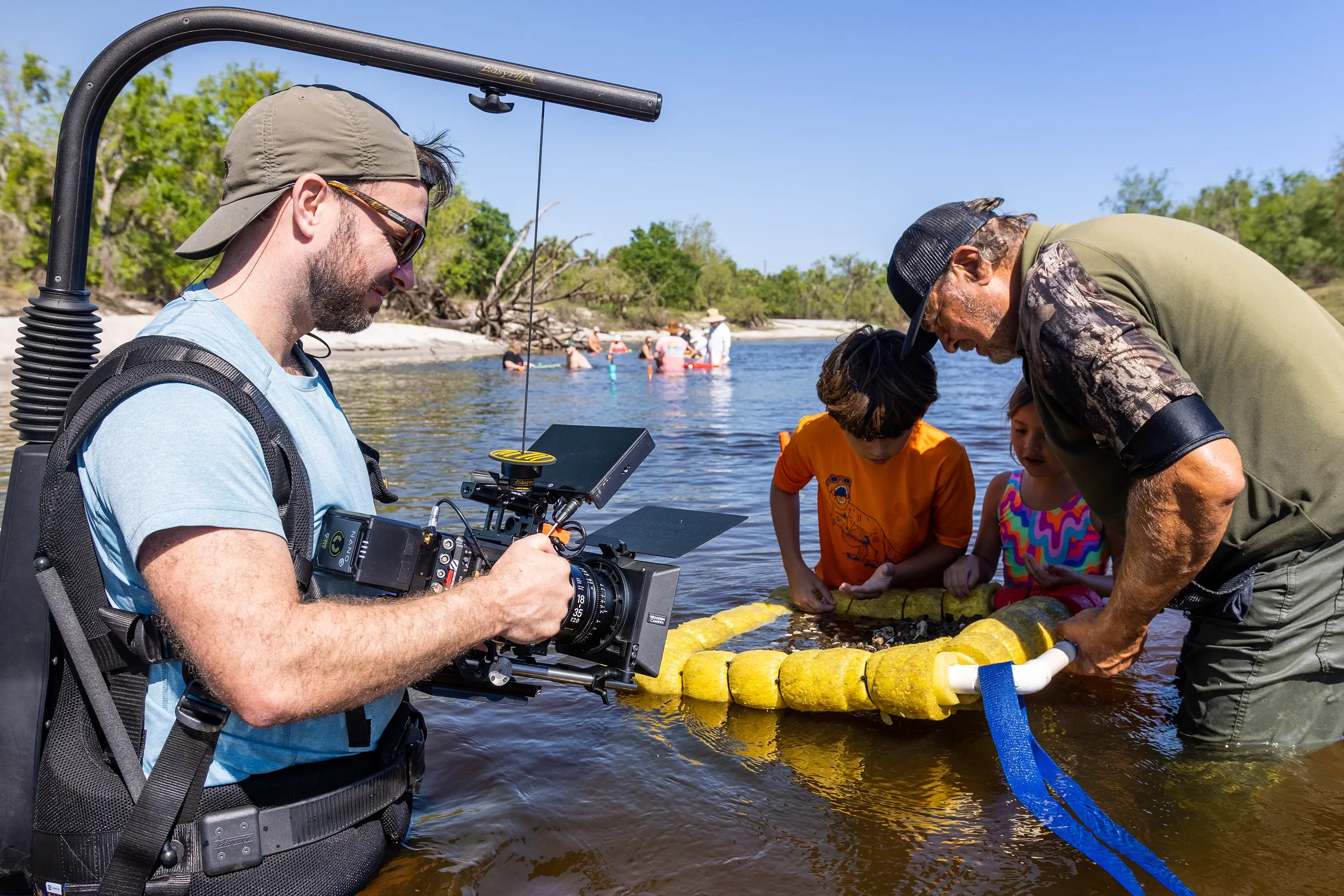 A photographer standing in a river with a family looking at rocks